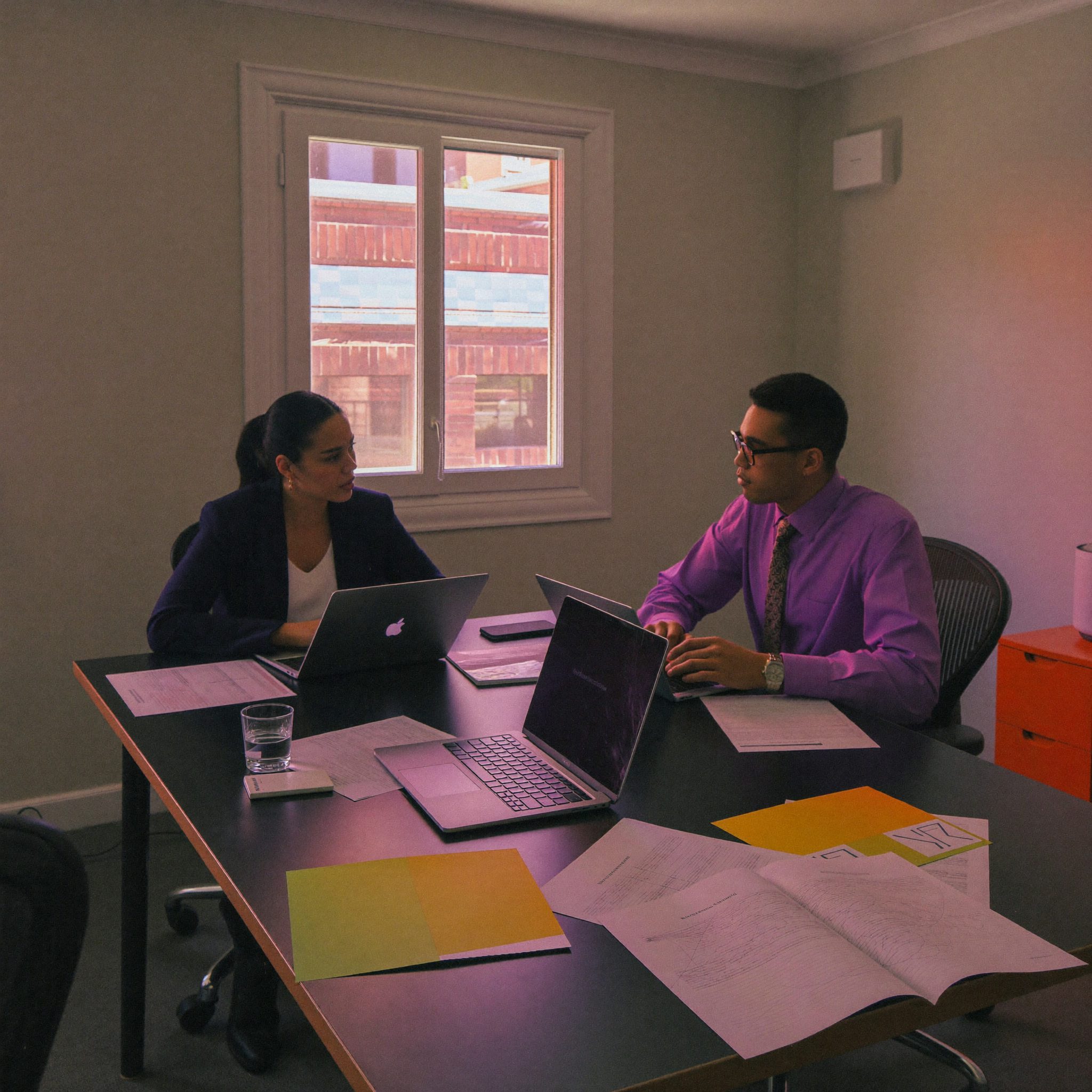 Two Kordavi advisors at a meeting table with laptops and printed statements